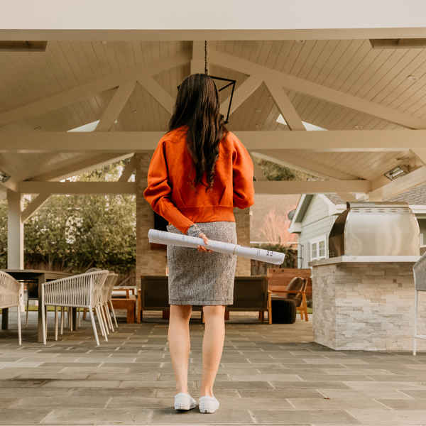 Lupe Monroy stands in an outdoor kitchen with blue prints behind her back