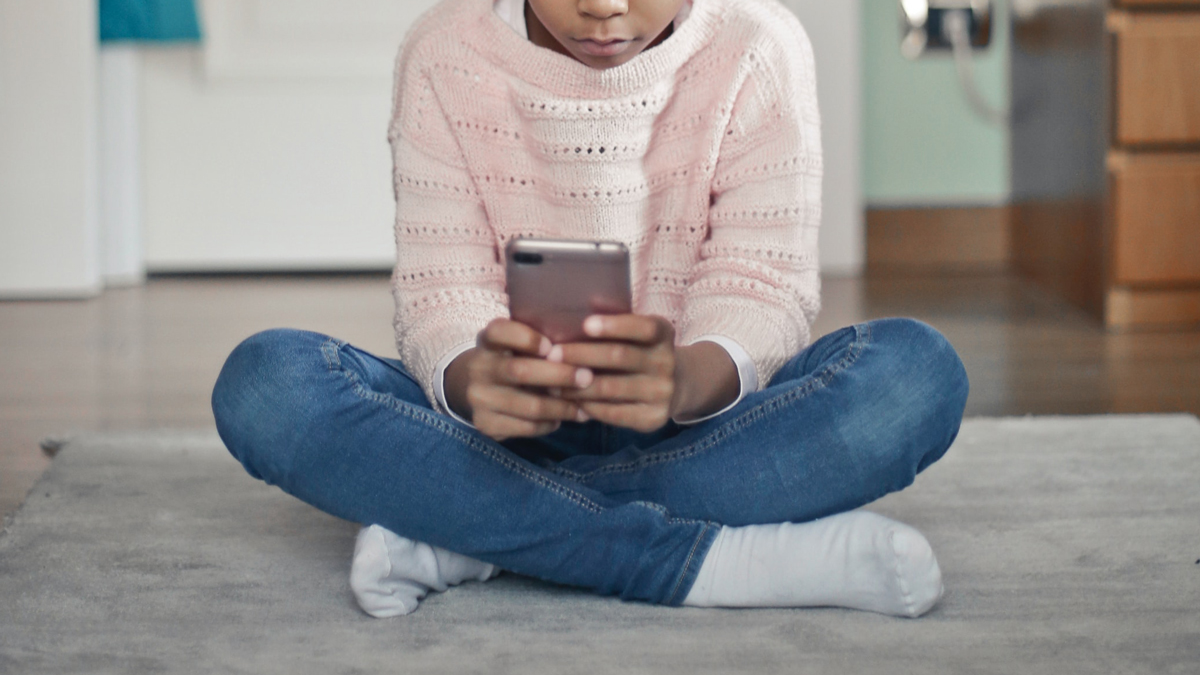 A young person sitting crosslegged and hold ing a smart phone