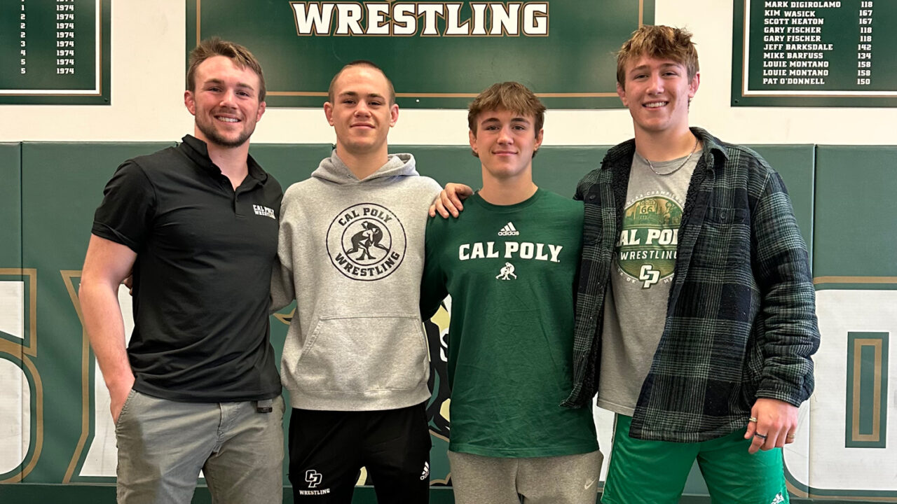 The four Lamer brothers stand and smile in the Cal Poly Wrestling room