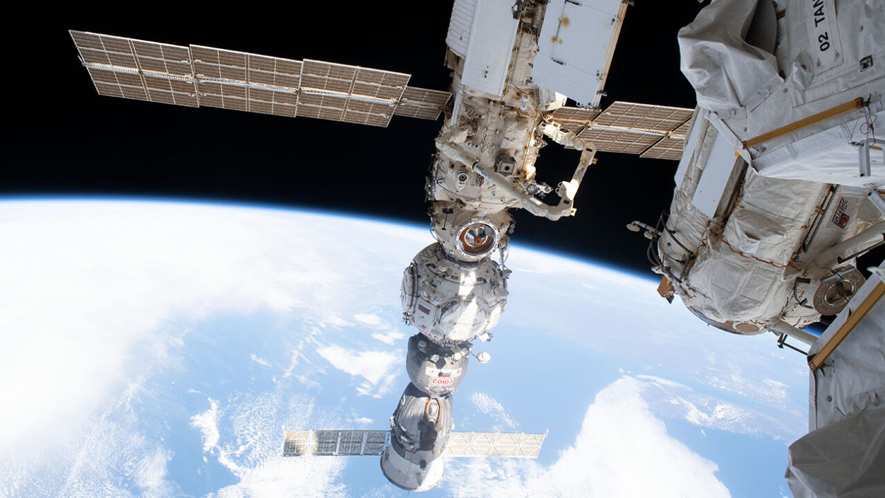 A photo of a section of the International Space Station suspended in orbit over the curve of the Earth
