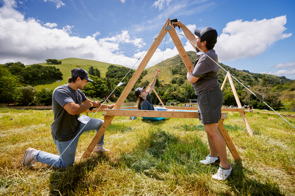 Three students assemble a wooden structure in Poly Canyon