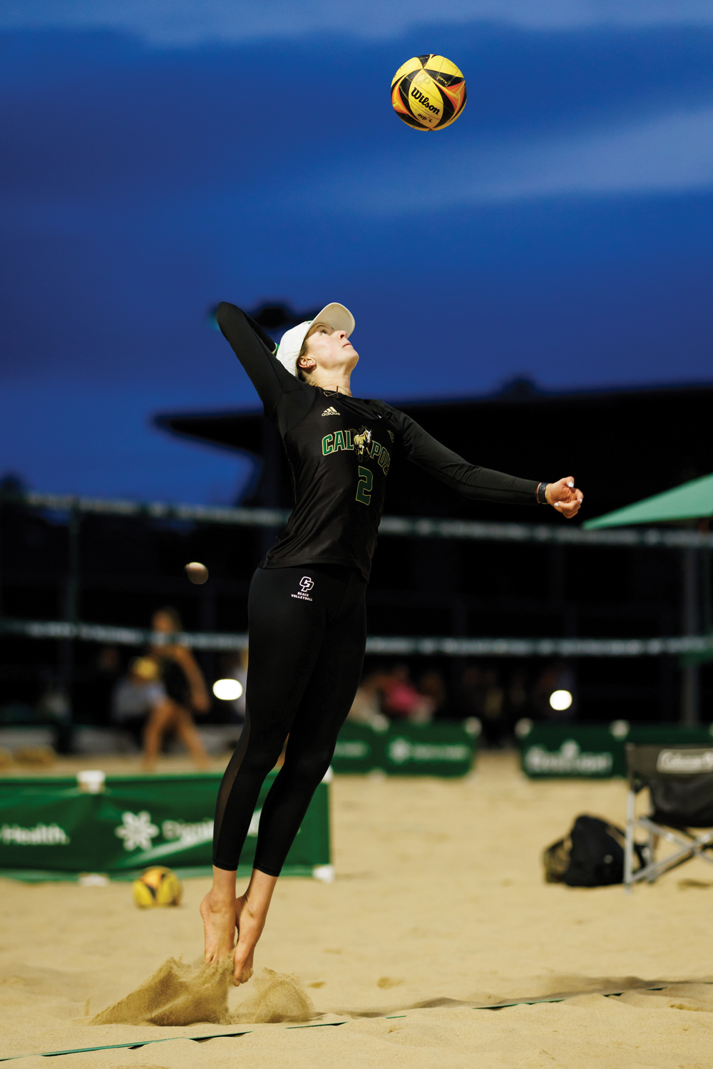 Beach volleyball player Ella Connor jumps as she serves on the sand