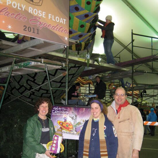 Three family members stand in front of the 2011 Cal Poly Rose Float "Galactic Expeditions" as it's being decorated