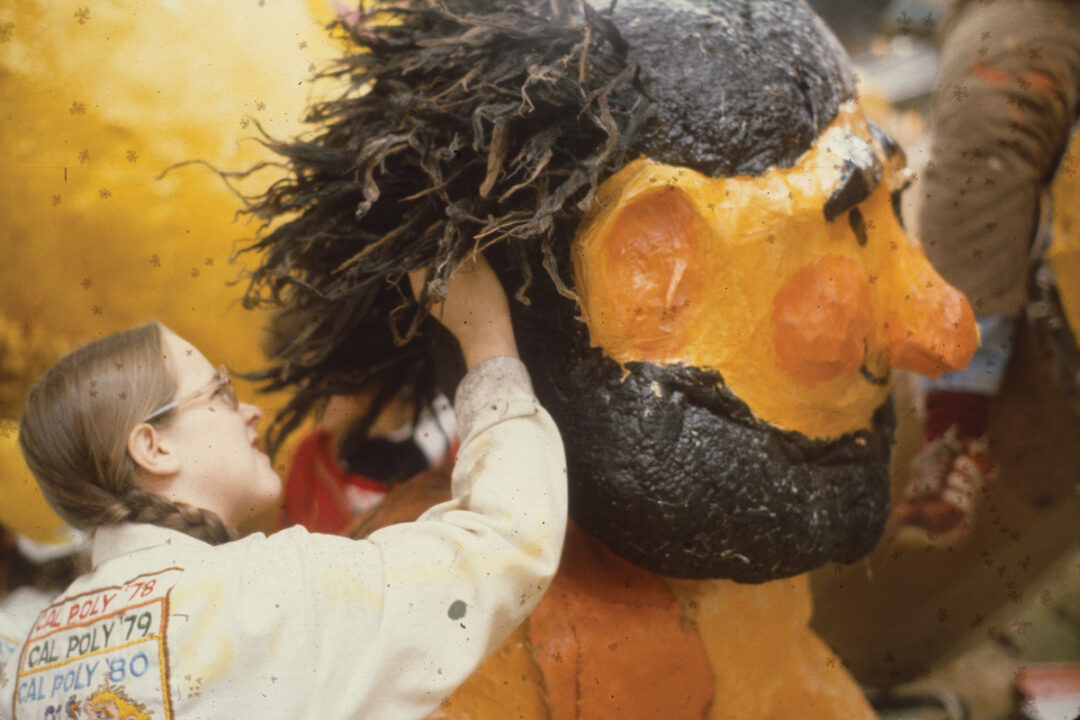 An archive image of a student decorating a caveman character on a Rose Parade float in 1979