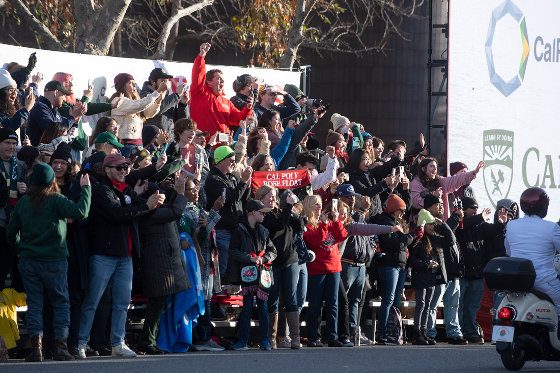 A crowd of people watch the Rose Parade from Colorado Boulevard