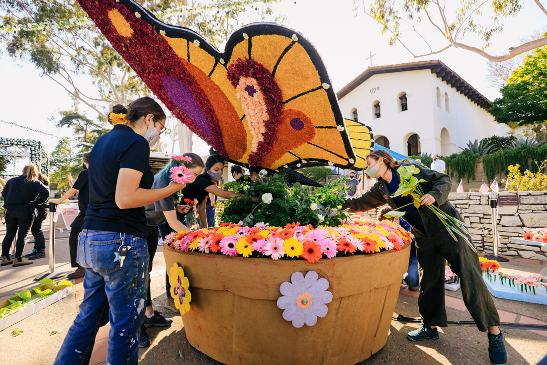 Students decorate a sculpture of a butterfly with flowers in San Luis Obispo's Mission Plaza