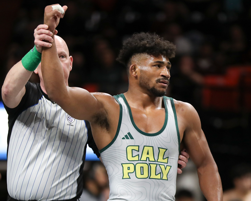 A referee raises the arm of a Cal Poly wrestler 