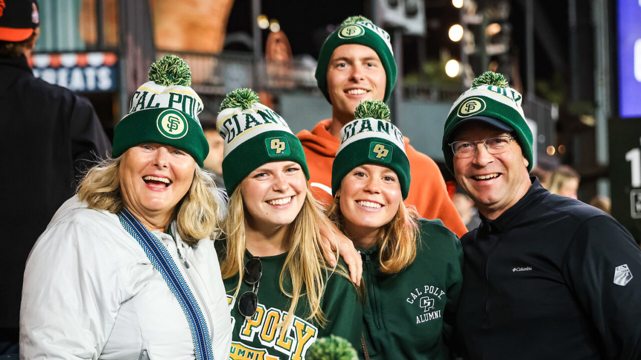 Five people smile while wearing green and gold Cal Poly beanies