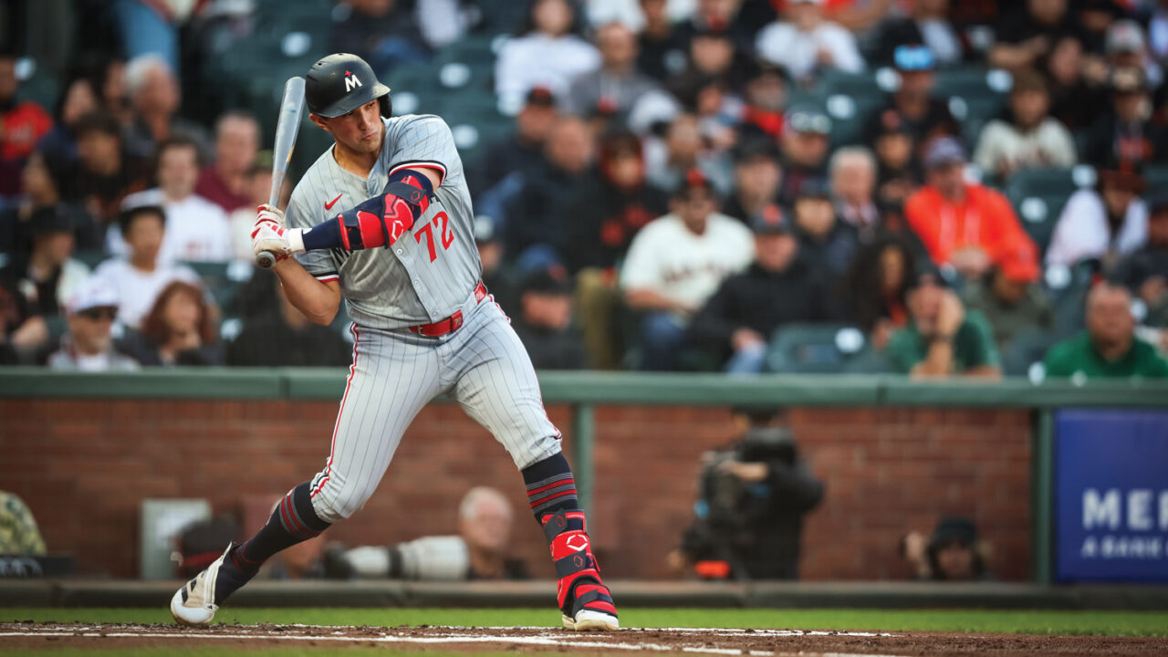 A baseball player swings the bat at home plate in a major league baseball stadium