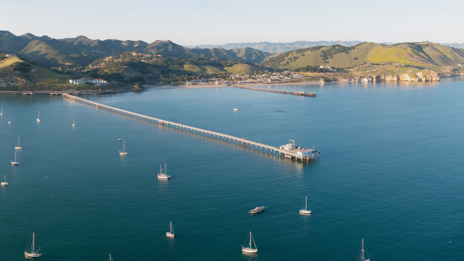 An aerial image of San Luis Obispo Bay and the Cal Poly Pier with boats in the marina