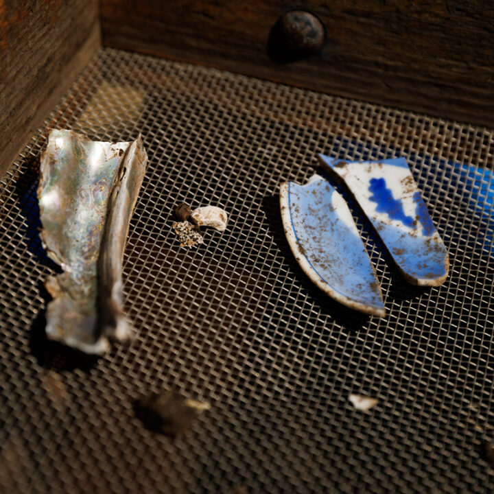 A shaker screen with a piece of metal and a broken piece of blue and white Japanese pottery