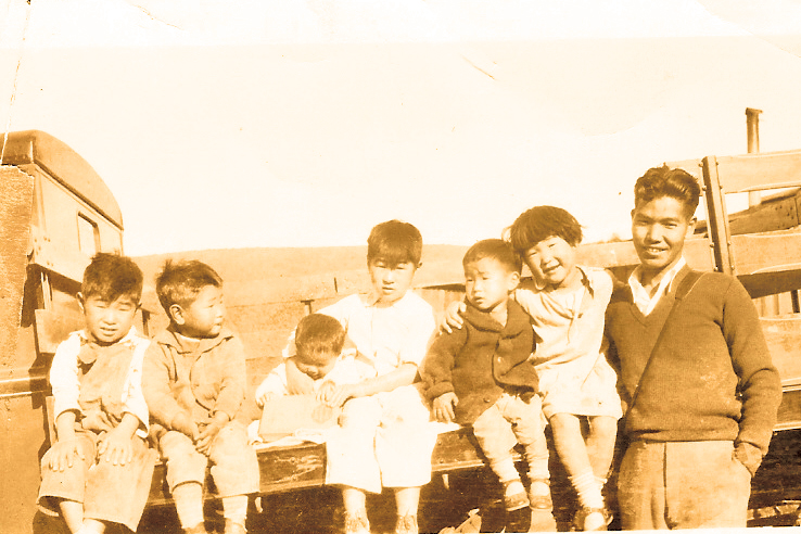 A black and white photo of six children and a teenager on a flat bed truck from the 1930s