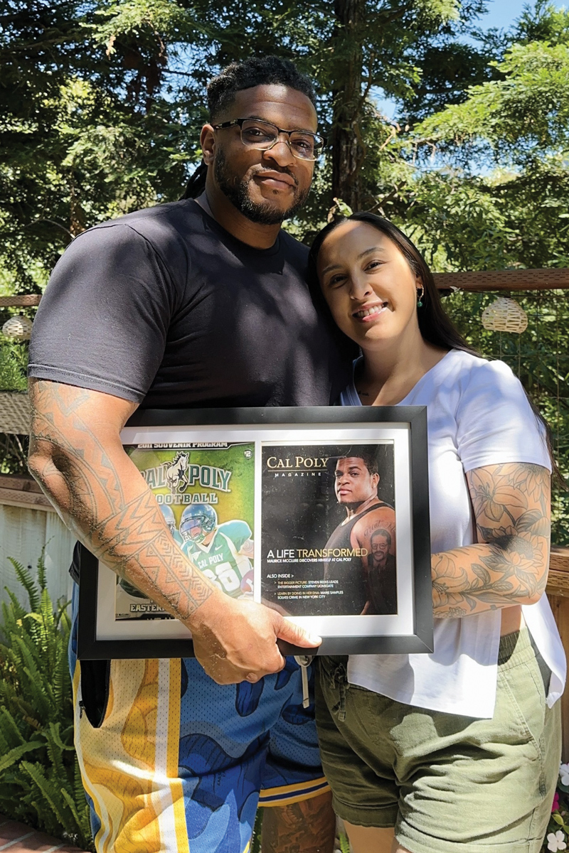 Two people stand embracing with a framed copy of Cal Poly Magazine