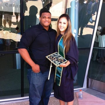 Two people, one person in cap and gown, embrace on the Cal Poly campus