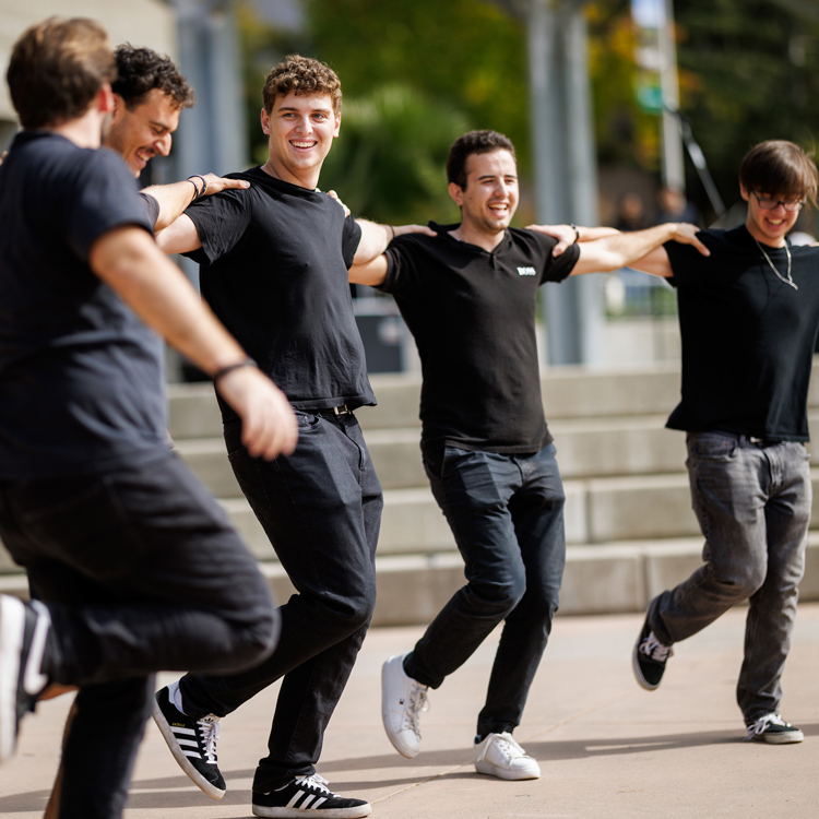 Men in black shirts link arms while dancing