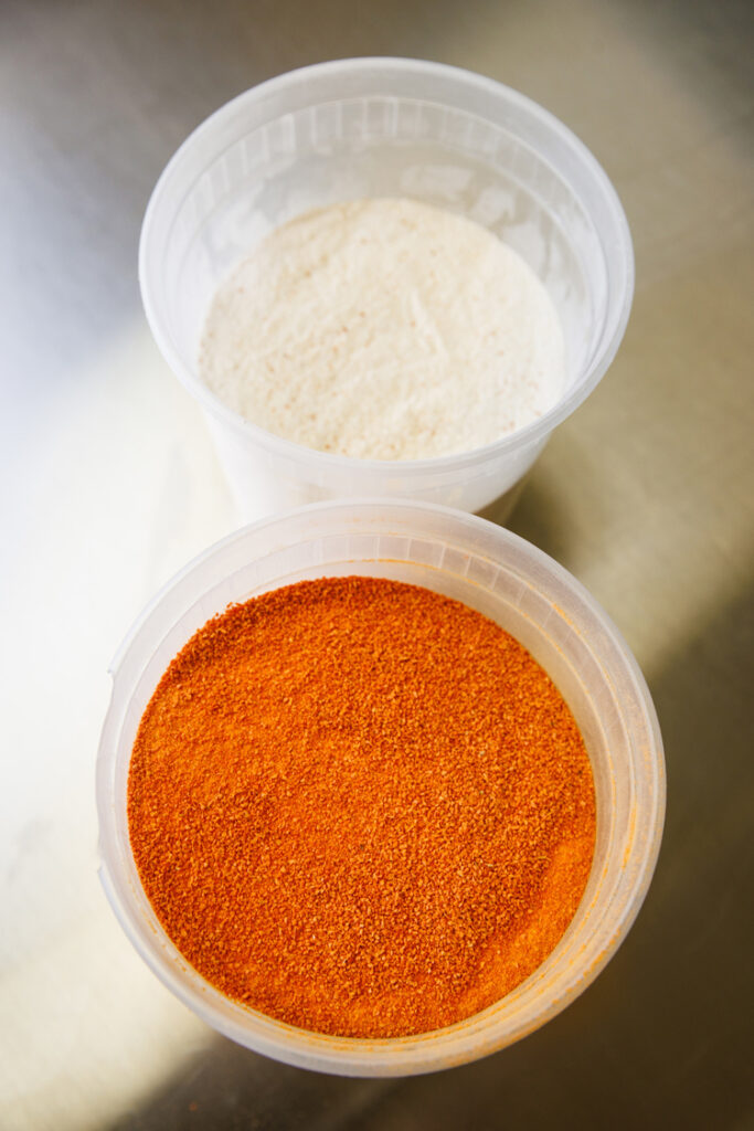 Two plastic containers of white and orange dry powder ingredients