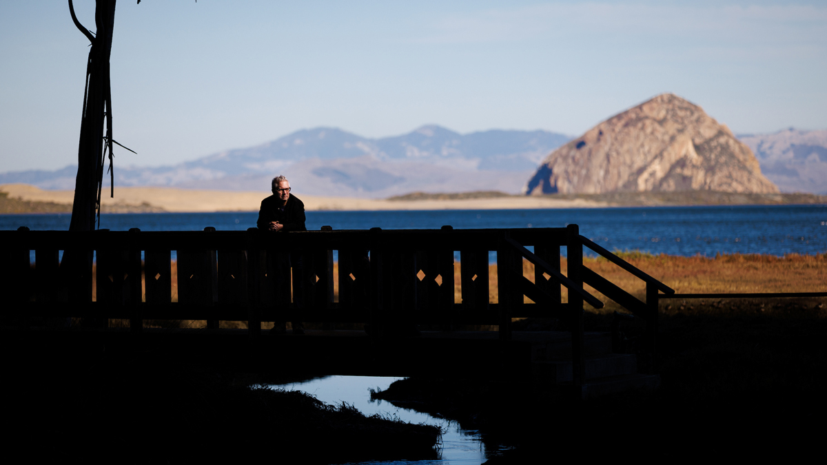 A man stands in shadow on a bridge near Morro Rock