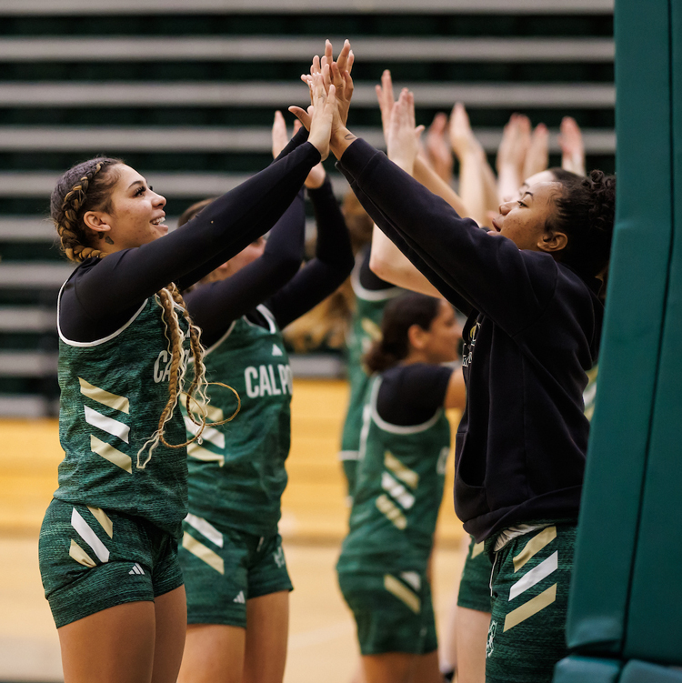 Women's basketball players give high fives to one another on the court