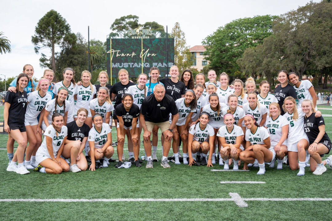 The Cal Poly women's soccer team poses for a photo in Spanos Stadium with Coach Alex Crozier at center