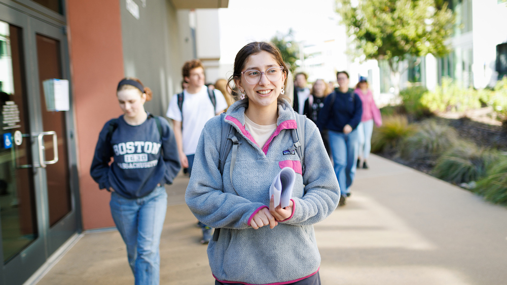 A student walks ahead of a group taking a tour on the Cal Poly campus