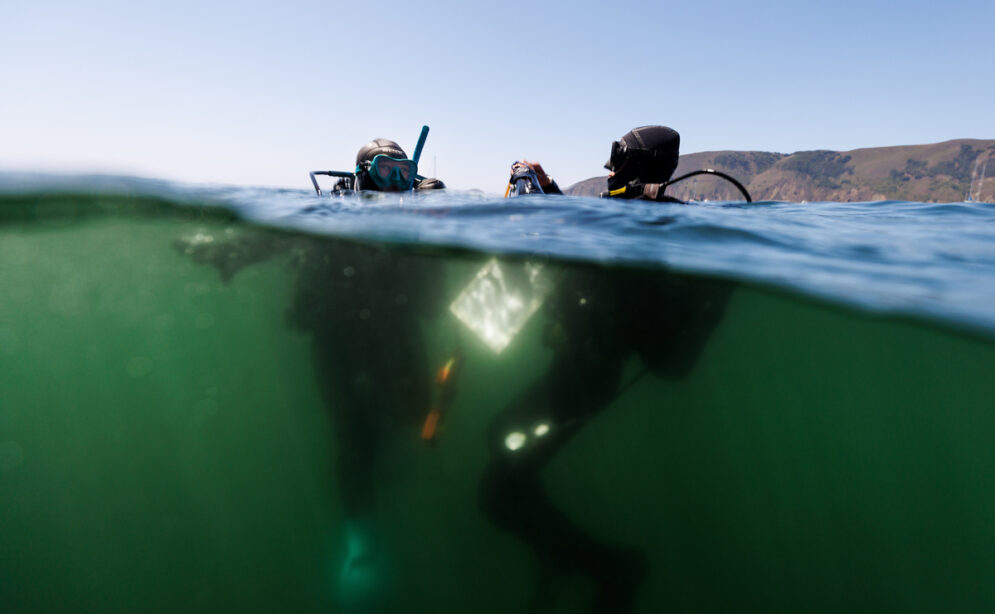 Two scuba divers with scientific equipment in the ocean