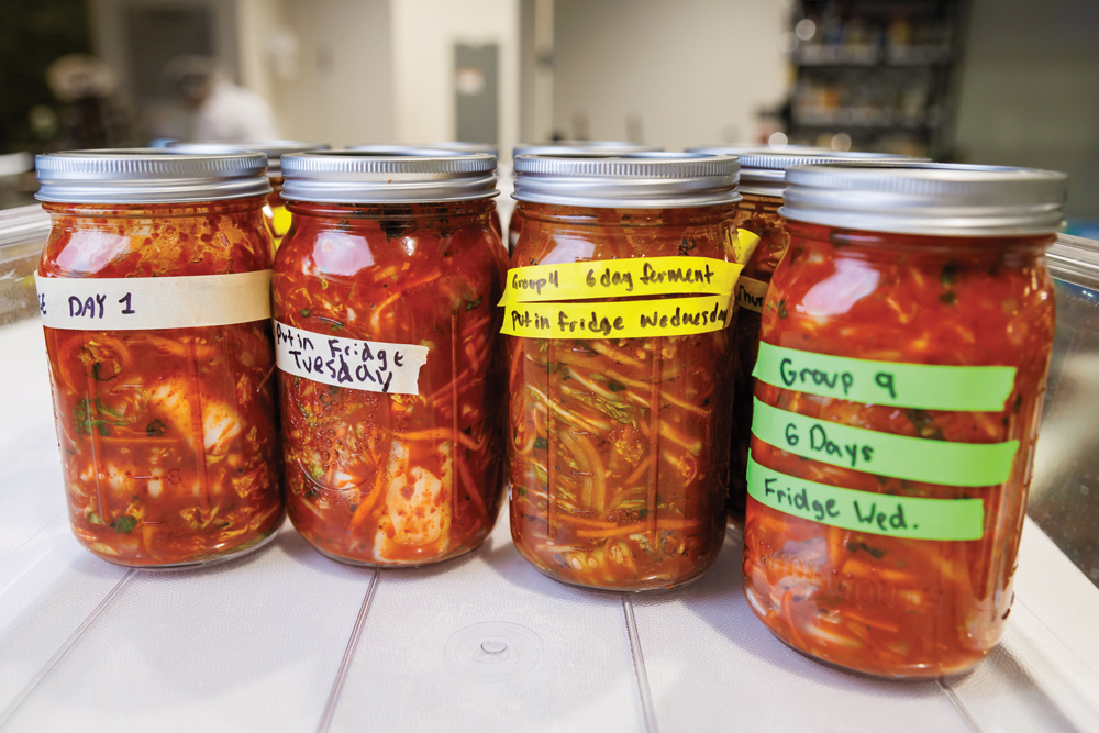 Four jars of kimchi with colorful, hand-written labels