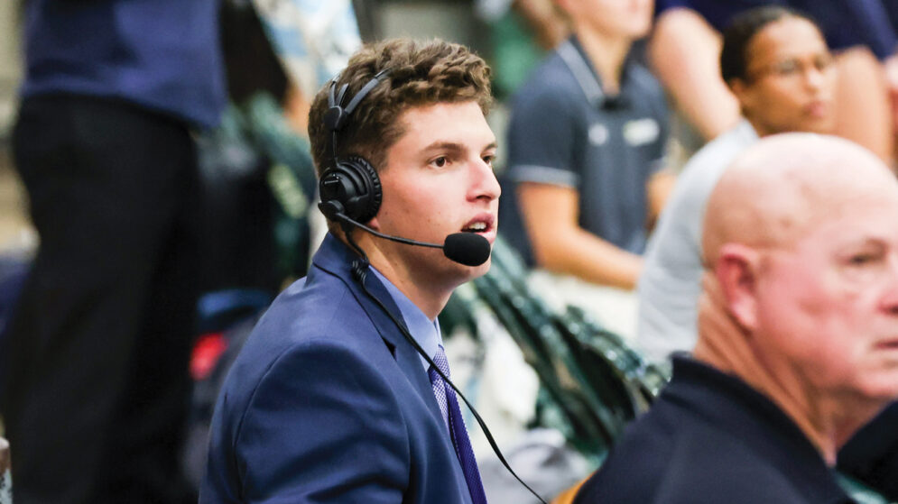 Harry Kaseff wears a headset on the sidelines of a women's volleyball game in Mott Gym
