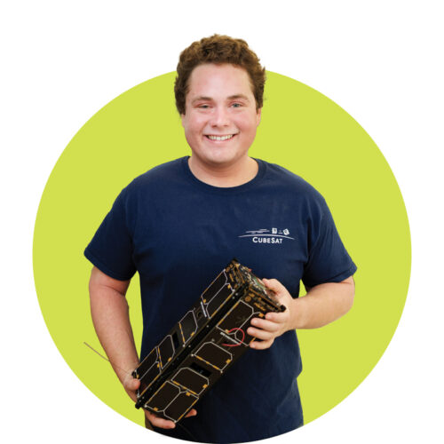 Ethan Spalard smiles while holding a small satellite