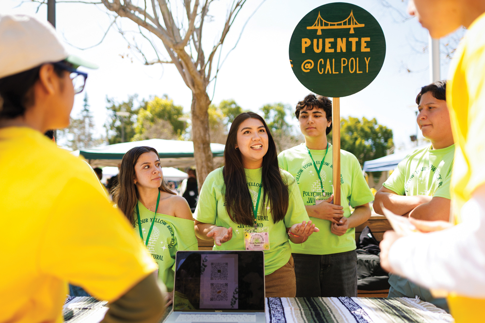 Students in Cal Poly's Puente chapter talks to prospective students at a booth in the University Union Plaza