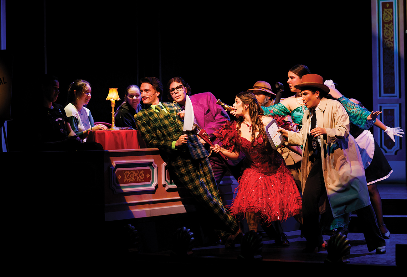 A cluster of colorfully-dressed characters lean dramatically toward several young women seated at a small table