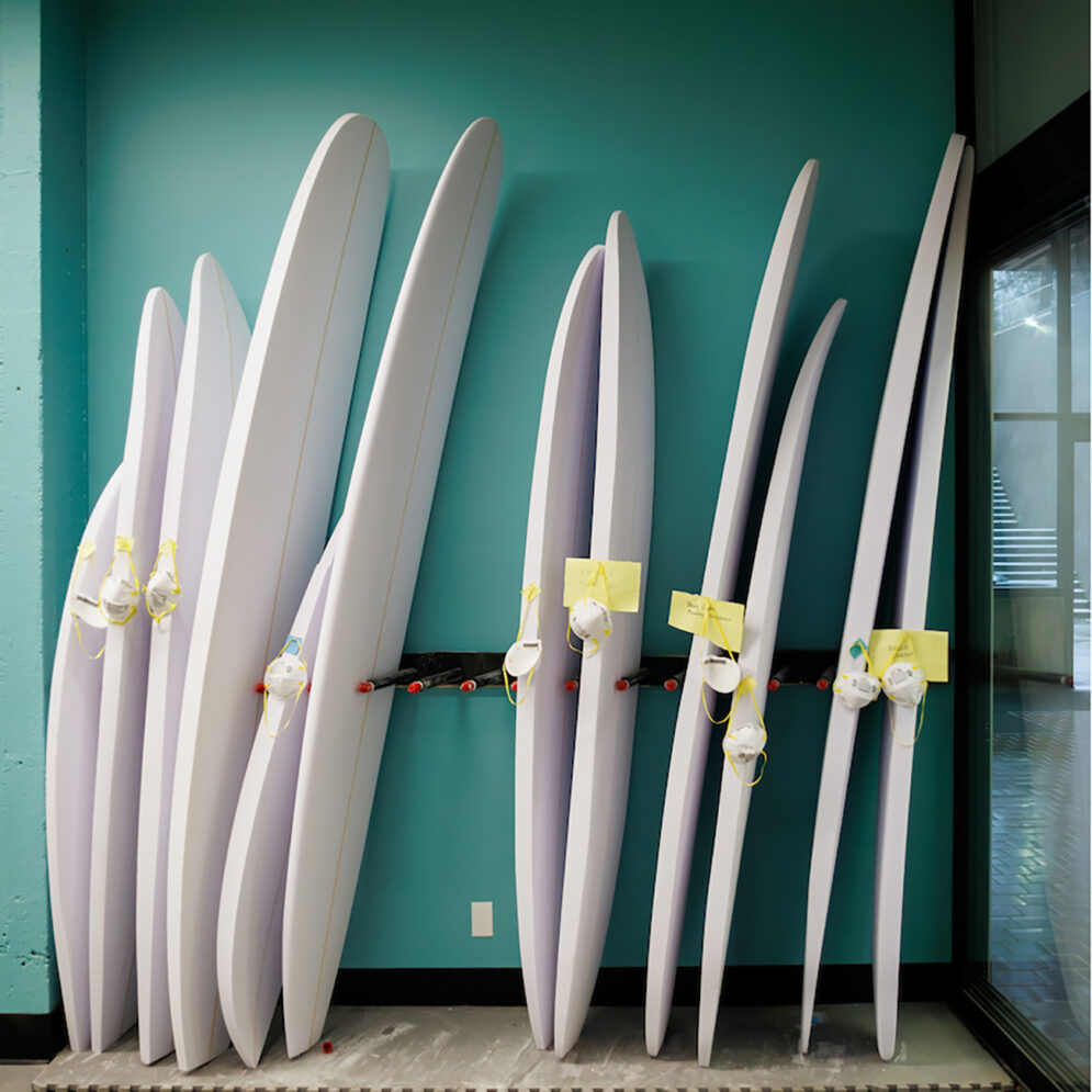 A rack holding a dozen unfinished surboards of various sizes and shapes.