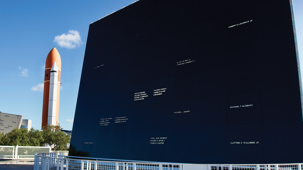 The Space Mirror Memorial with a rocket positioned vertically on a launch pad in the background.