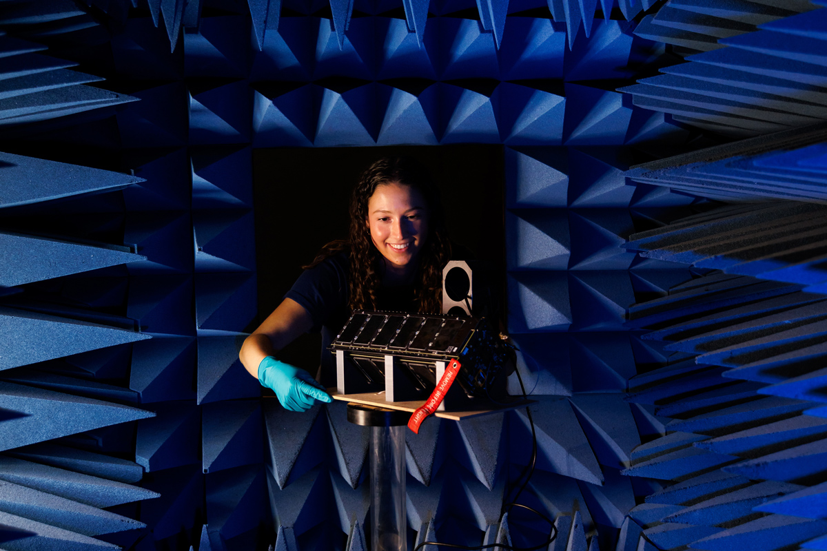 A student positions the CubeSat payload in an anechoic chamber for testing.