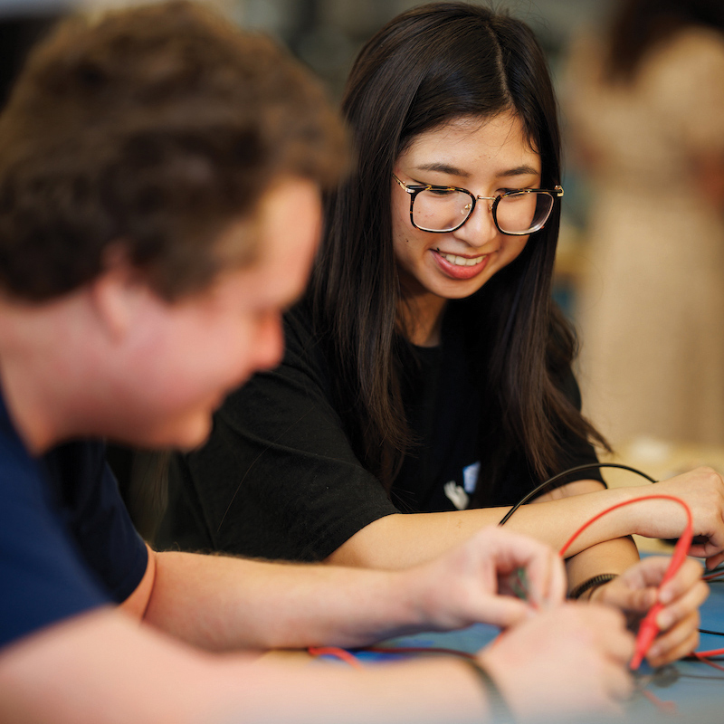 Two students test a circuit board in an engineering laboratory