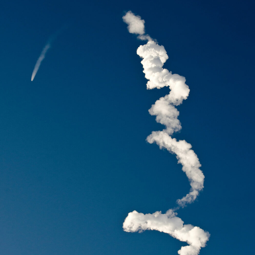 The trail of a rocket launched into the blue sky above Vandenberg Space Force Base.