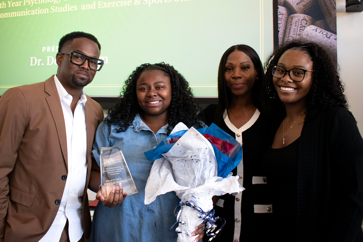 A Cal Poly student accepts an award with three family members by her side