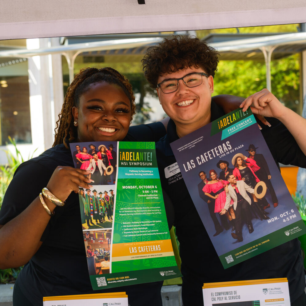 Two student assistants host a booth at Cal Poly holding printed materials