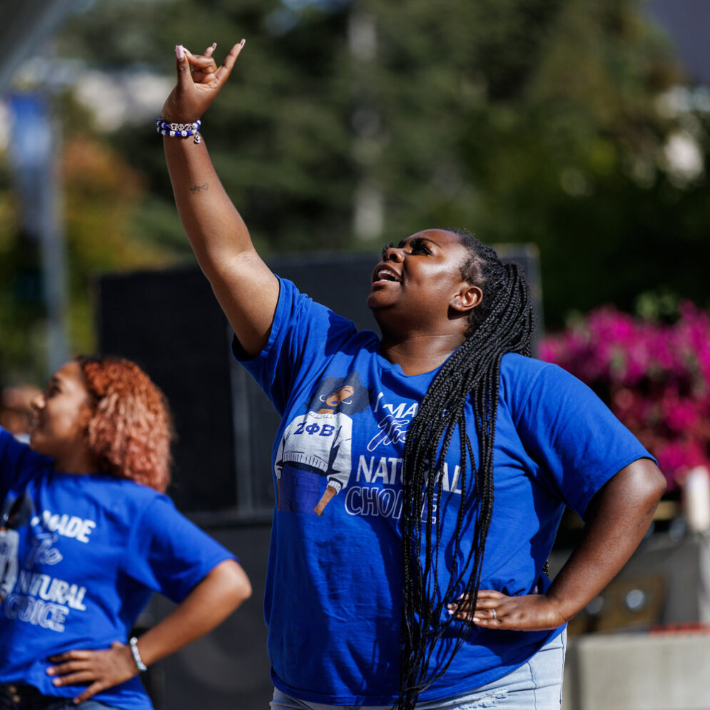 Two sorority members wearing blue shirts dance at the Cal Poly Culturefest event