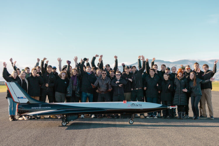A two dozen people cheer near a space plane on a runway