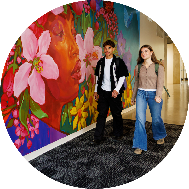 Two people walking near a vibrant mural