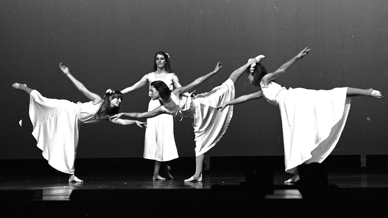 An archive image of Cal Poly Orchesis dancers in white dresses performing on stage