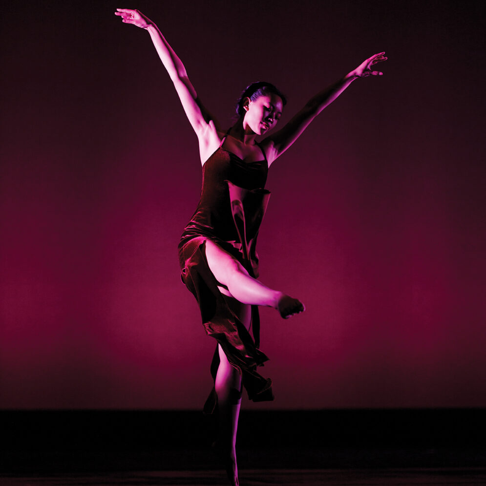 A dancer in a purple dress strikes a pose on stage