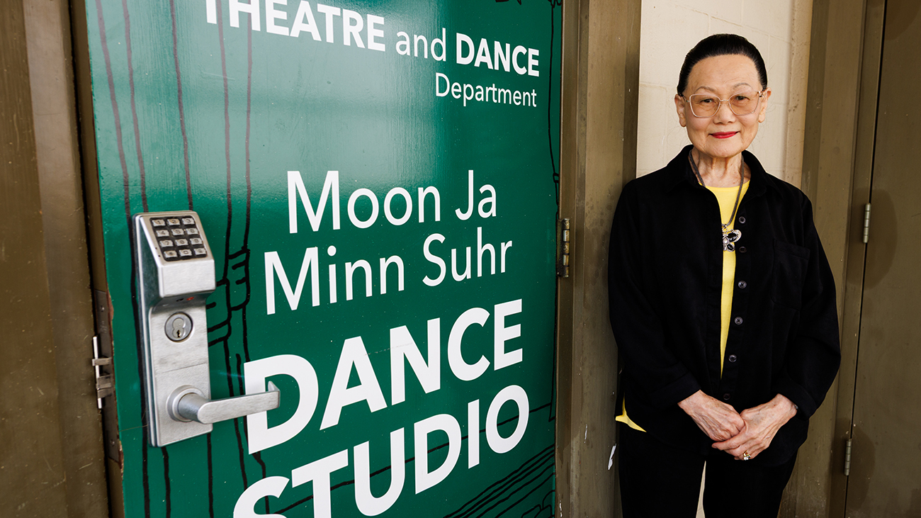 Emeritus professor Moon Ja Minn Suhr outside a green door of the dance studio named for her