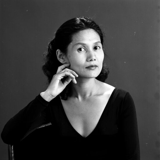 A black and white portrait of a woman resting her hand on her cheek