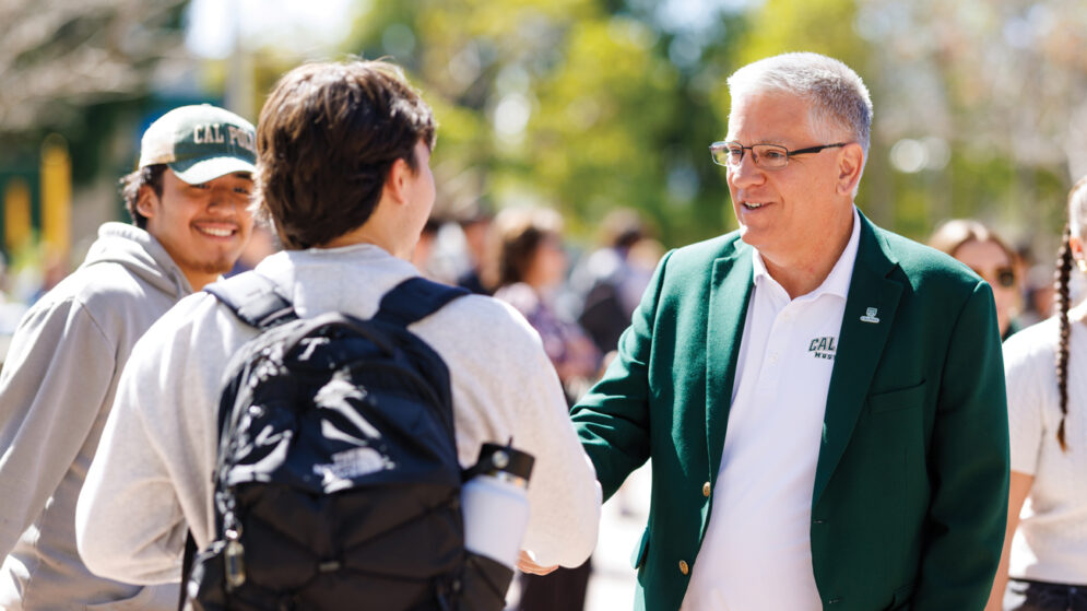 President Jeffrey D. Armstrong wearing a green blazer and shaking hands with students