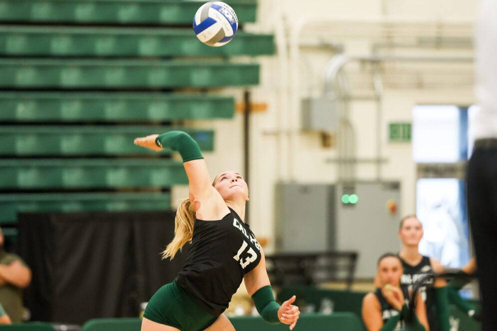 A volleyball player serves the ball in Mott Gym