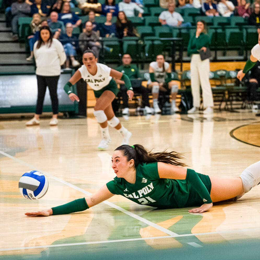 A Cal Poly Volleyball player dives for the ball on the court