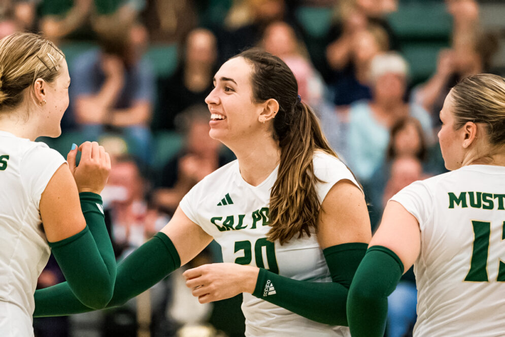 A Cal Poly Volleyball player high fives a team mate while on the court in Mott Gym