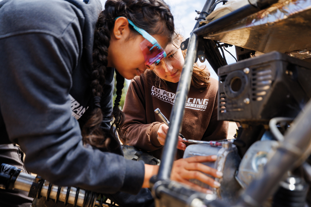Two Cal Poly Racing team members repair a Baja vehicle during a testing session