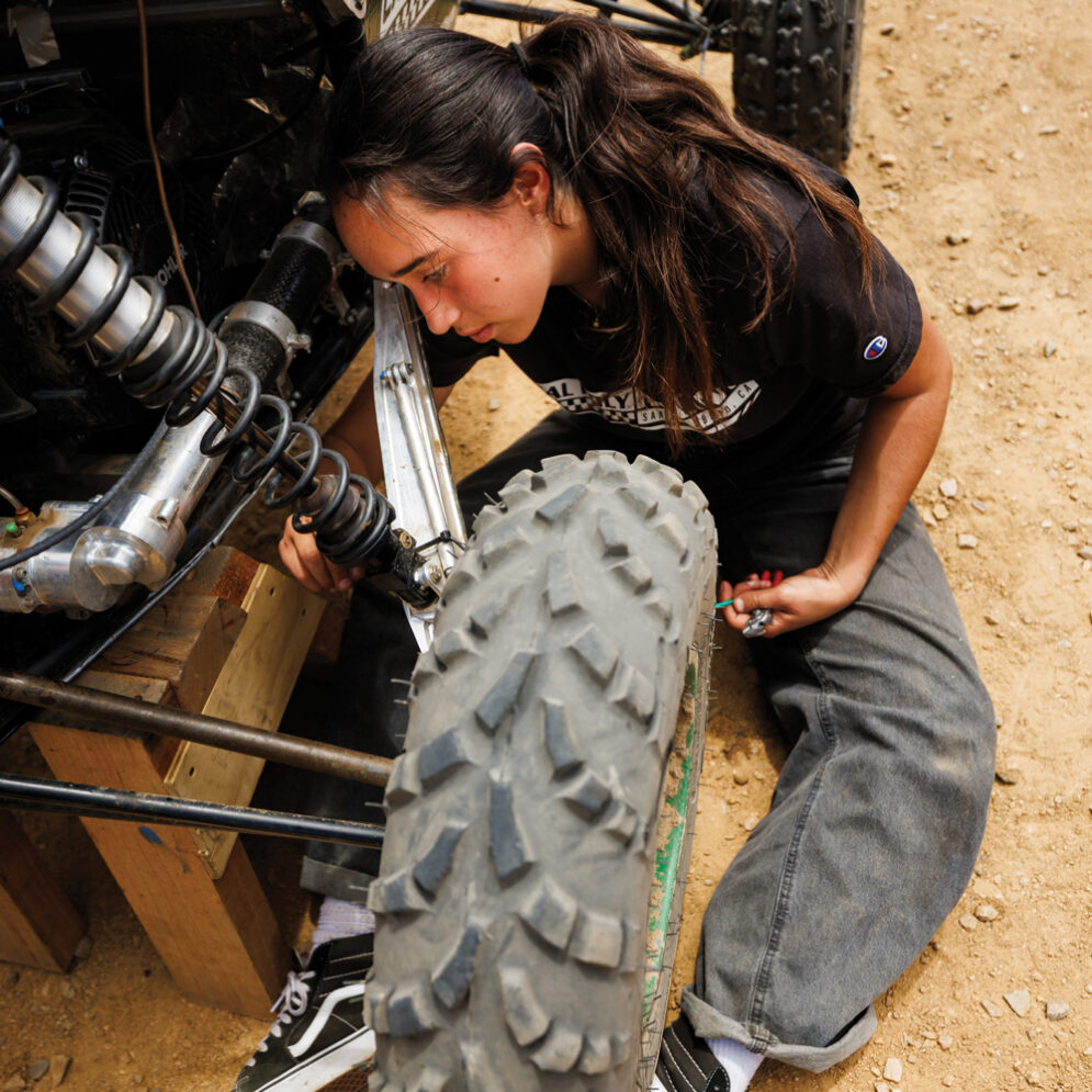 A Cal Poly Racing team member repairs the wheel and suspension of a Baja vehicle during a testing session